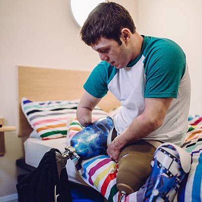 Quadriplegic male putting his prosthetic legs on in his student accomodation.